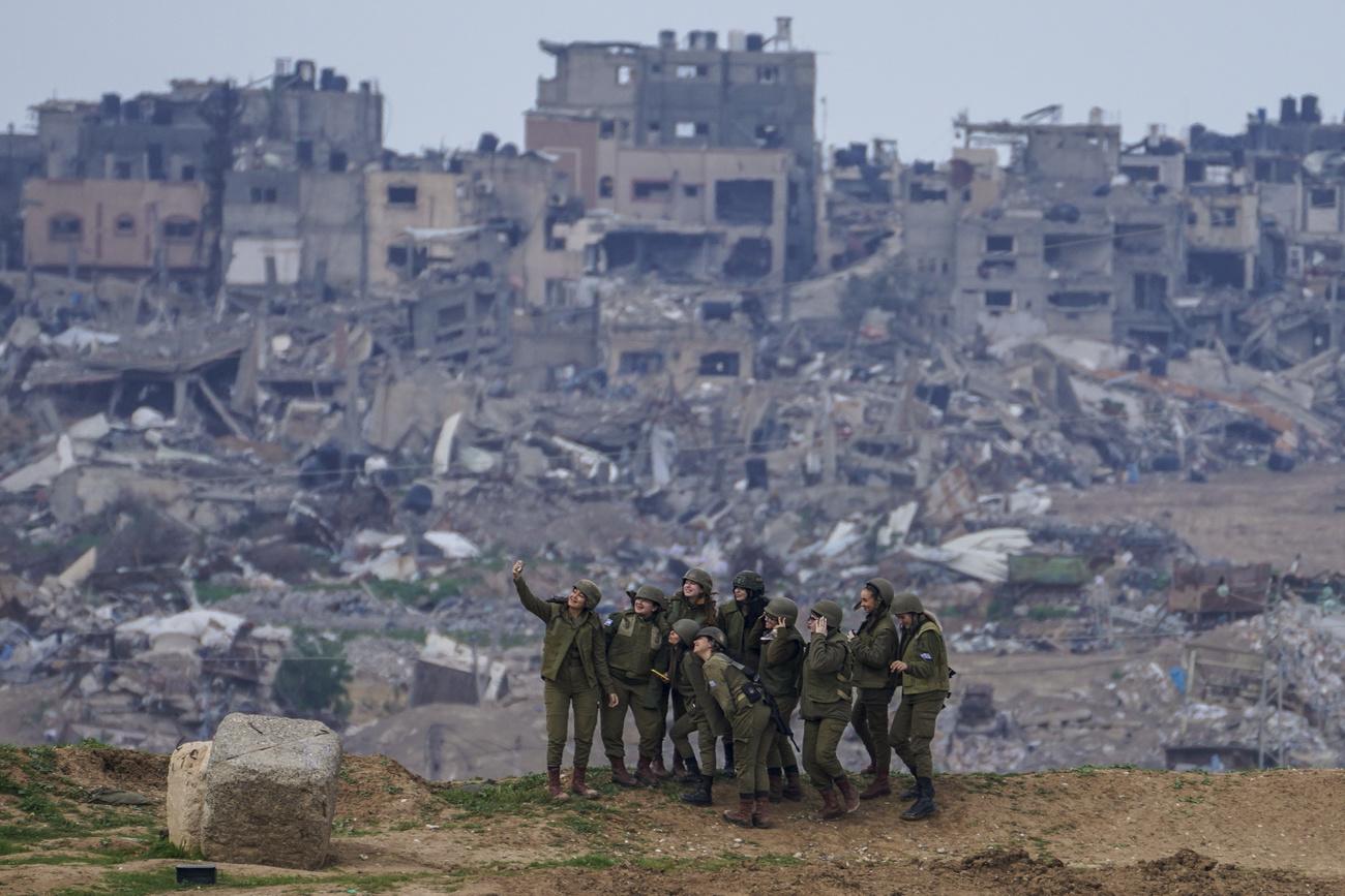 Des militaires israéliennes posent pour une photo sur une position à la frontière de la bande de Gaza, dans le sud d'Israël, lundi 19 février 2024. [KEYSTONE - TSAFRIR ABAYOV]