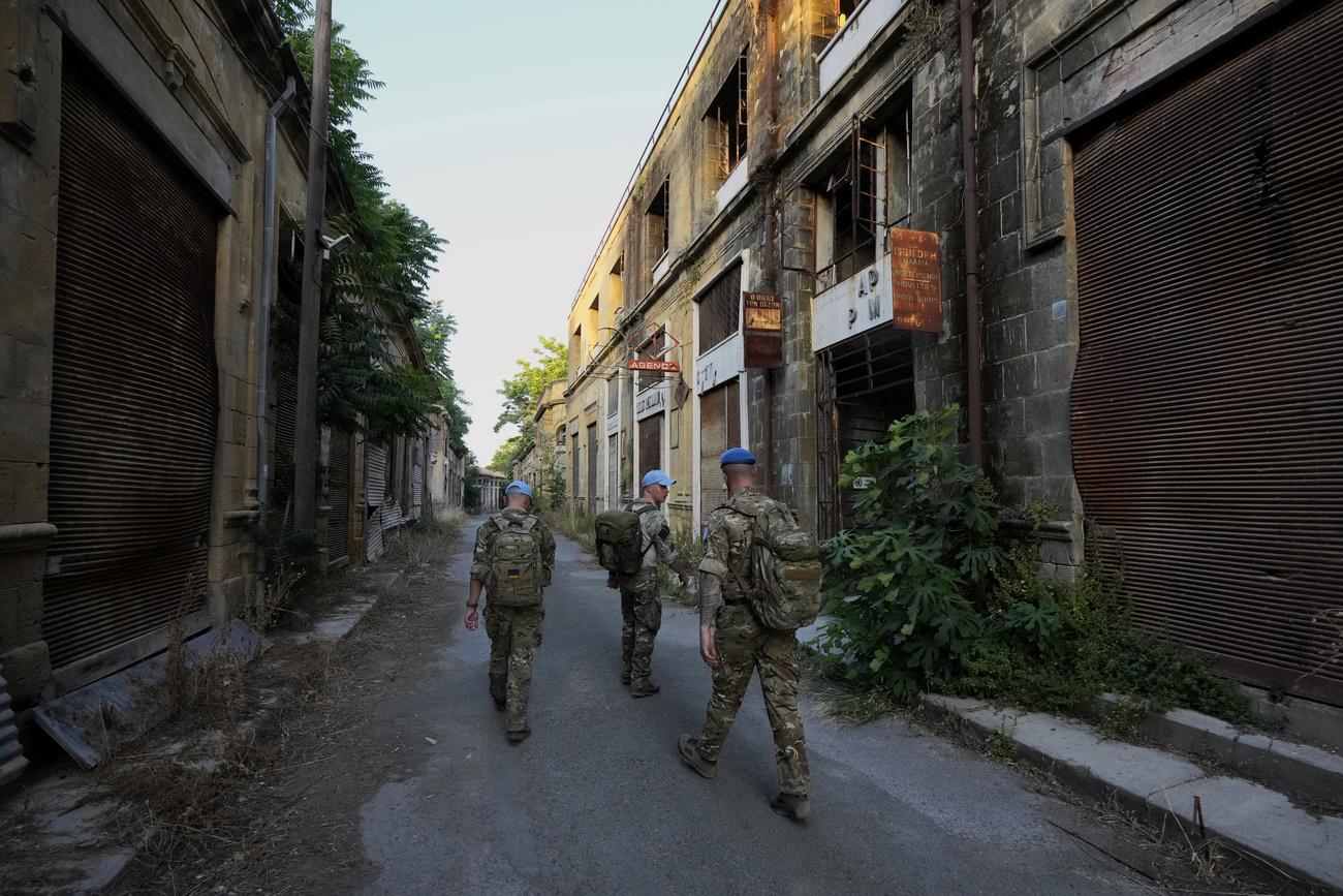 Des casques bleus patrouillent dans une rue abandonnée de Nicosie, capitale divisée par la "ligne verte" sous surveillance de l'ONU, le 18 juin 2024. [KEYSTONE - PETROS KARADJIAS]