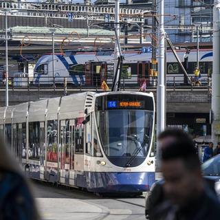 Des personnes passent devant un tram des Transports publics genevois (TPG). [Keystone - Martial Trezzini]