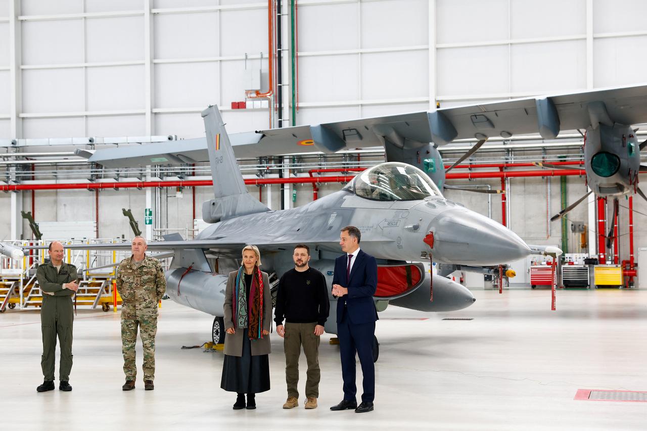 Le président ukrainien Volodymyr Zelenskiy, le Premier ministre belge Alexander de Croo et la ministre de la Défense belge Ludivine Dedonder se tiennent devant un avion F-16 à la base aérienne de Melsbroek, près de Bruxelles, le 28 mai 2024 (image d'illustration). [REUTERS - Piroschka Van De Wouw]