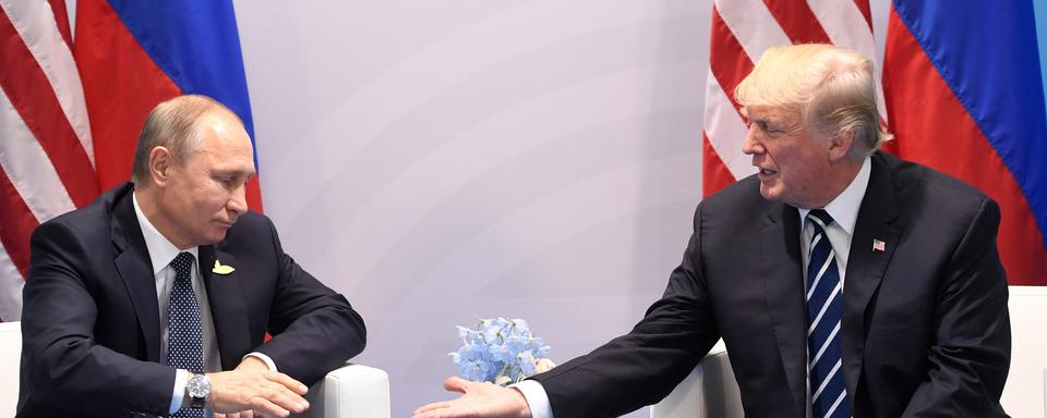 L'ex président américain Donald Trump et le président russe Vladimir Poutine se serrent la main lors d'une rencontre en marge du sommet du G20 à Hambourg, en Allemagne, le 7 juillet 2017. [AFP]