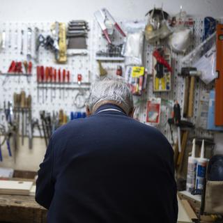 Un retraité âgé continuant à travailler dans son atelier. [Keystone - Christian Beutler]