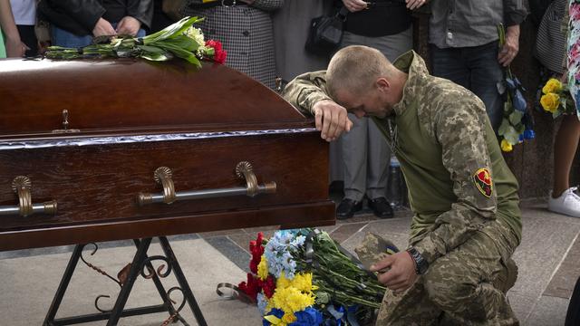 Un soldat ukrainien rend un dernier hommage au cercueil de son camarade, tué lors d'une bataille contre les troupes russes, lors de la cérémonie funéraire sur la place de l'Indépendance à Kiev, en Ukraine, le lundi 6 mai 2024. [KEYSTONE - EFREM LUKATSKY]