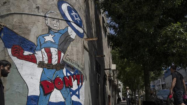 Un graffiti présentant le président américain Joe Biden tenant un bouclier pour protéger Israël, dans les rues de Tel-Aviv. [KEYSTONE - LEO CORREA]