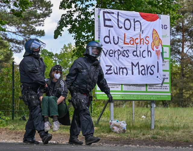 Une manifestante en train d'être évacuée par la police vendredi, près du site de stockage des voitures Tesla à leur sortie d'usine. [KEYSTONE - PATRICK PLEUL]