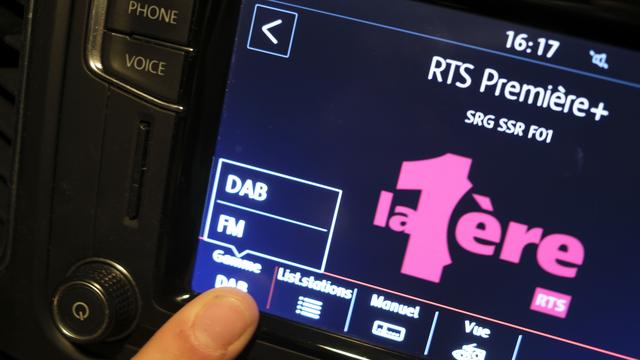 Une personne commute un autoradio de la FM au DAB. Le 31 décembre 2024, les fréquences FM des radios de la SSR seront supprimées. Celles-ci ne pourront alors plus être captées que via DAB+ et Internet. [Keystone - Laurent Gillieron]