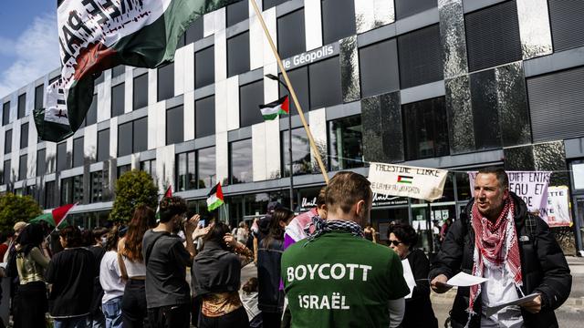 Joseph Daher, professeur invité à l'université de Lausanne, distribue des documents aux militants pro-palestiniens qui occupe un bâtiment de l'Unil. [Keystone - Jean-Christophe Bott]