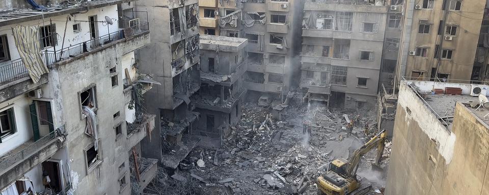 Rescue workers use an excavator to clear the rubble of destroyed buildings, as they search for victims at the site of Thursday's Israeli airstrike, in Beirut, Lebanon, Friday, Oct. 11, 2024. [AP Photo/Keystone - Hussein Malla]