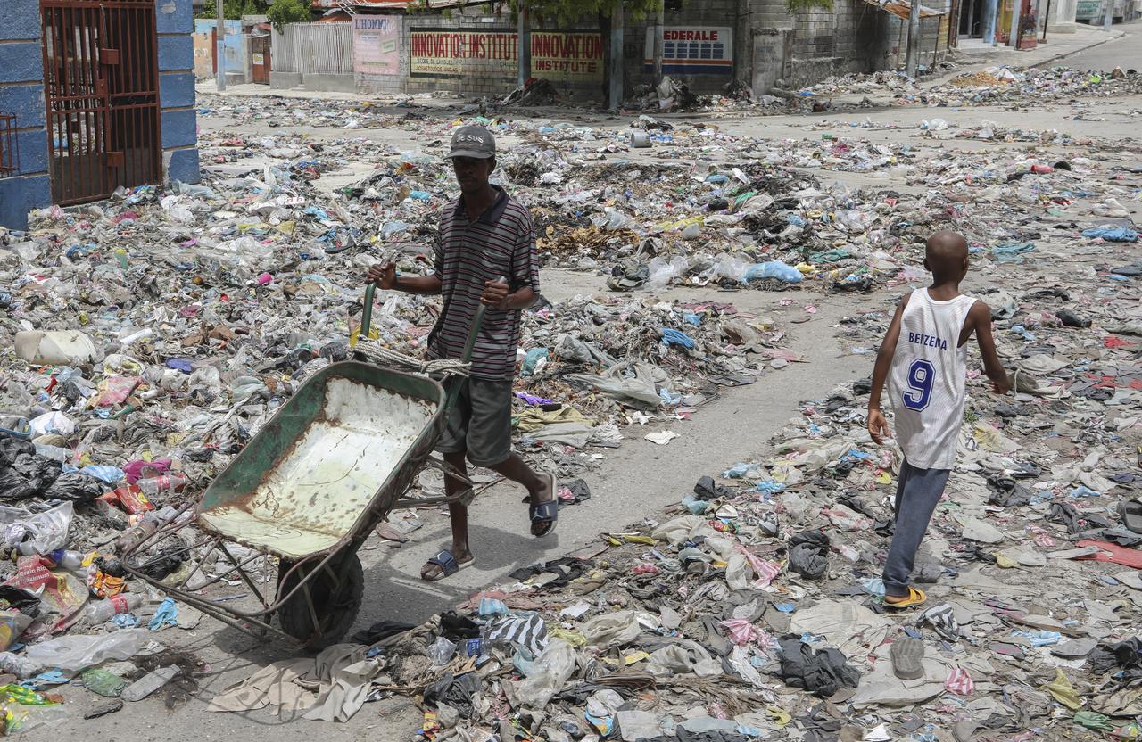 Des gens marchent dans une rue couverte d'ordures dans le centre de Port-au-Prince, Haïti, jeudi 5 septembre 2024. [KEYSTONE - ODELYN JOSEPH]