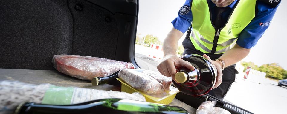 Un garde-frontière contrôle de la marchandise dans le coffre d'une voiture. [Keystone - Laurent Gillieron]