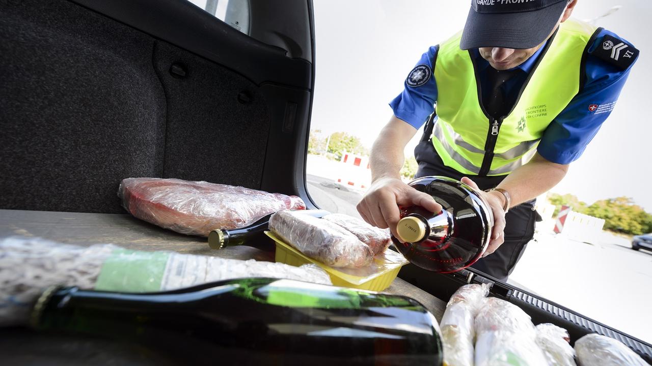 Un garde-frontière contrôle de la marchandise dans le coffre d'une voiture. [Keystone - Laurent Gillieron]