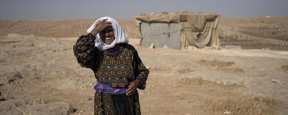 Une femme âgée palestinienne prend la pose devant sa maison à Masafer Yatta à Gaza. [Keystone/AP Photo - Maya Alleruzzo]