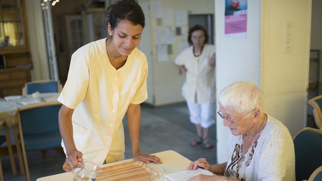 Lucie, une infirmiere, donne de l'eau a boire a Charlotte, une personne agee de l'Etablissement Medico-Social, EMS, "Le Marronnier", ce jeudi 25 juillet 2013 a Lutry. Un avis de canicule est lance par meteo suisse, une vague de chaleur se produira durant ces prochains jours. (KEYSTONE/Jean-Christophe Bott) [Keystone - Jean-Christophe Bott]