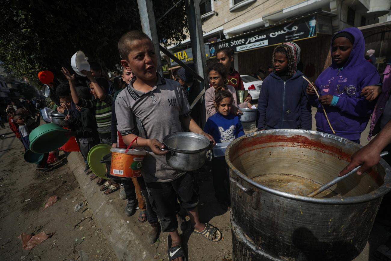 Des enfants font la queue pour manger à Deir Al Balah, dans le sud de la bande de Gaza. [KEYSTONE - MOHAMMED SABER]