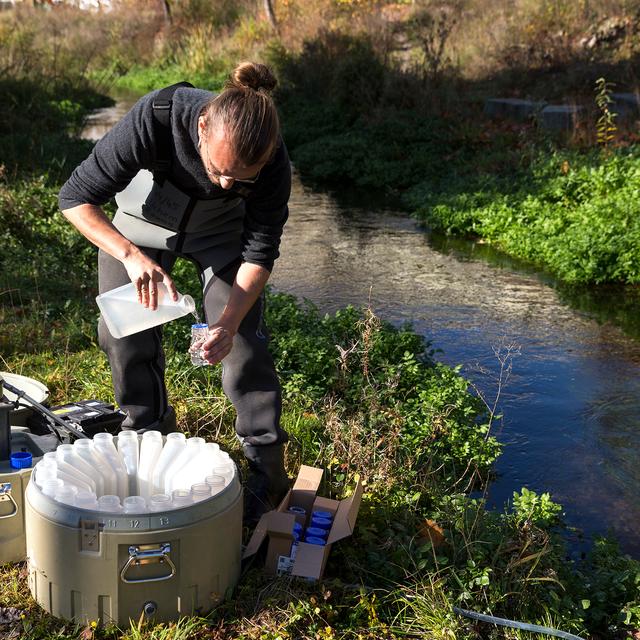 Un chercheur de l'Eawag effectue un prélèvement d'échantillons dans un ruisseau. [VSA - Della Bella]