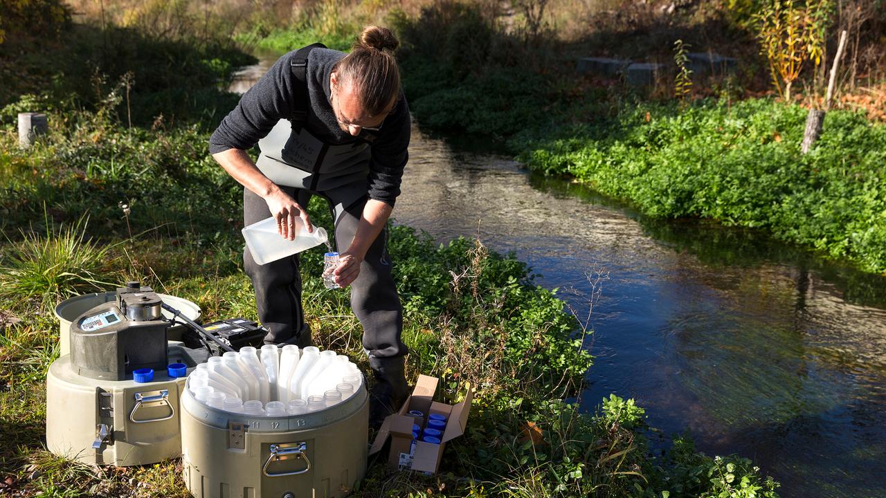 Un chercheur de l'Eawag effectue un prélèvement d'échantillons dans un ruisseau. [VSA - Della Bella]