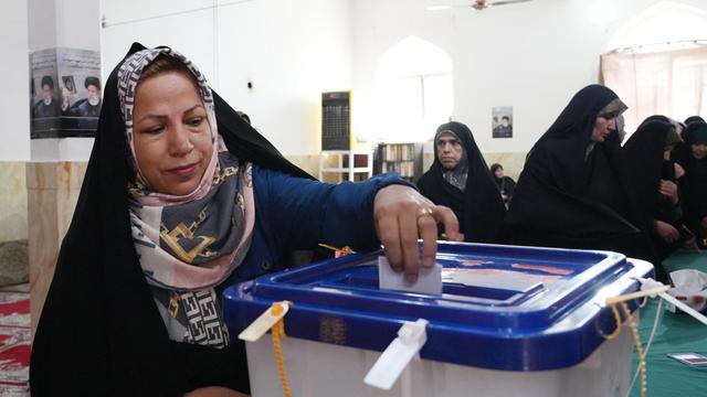 Une femme iranienne glisse son bulletin dans l'urne pour l'élection présidentielle, le 28 juin 2024 à Téhéran. [AFP - RAHEB HOMAVANDI]