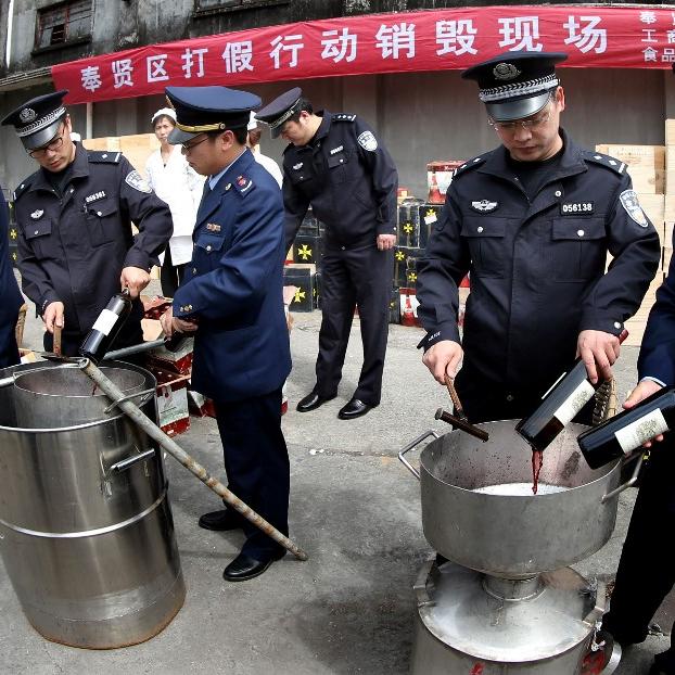 Vac mensonge 5/5: A Shanghaï, la police détruit 3'000 bouteilles de vin de contrefaçon en 2013. [AFP - Fan Jun]