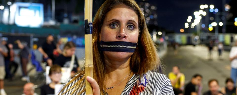 A woman, wearing a zipper-shaped gag, attends a silent protest with families of hostages held in Gaza, marking one year since the October 7 attack by Hamas during which their loved ones were taken hostage, in Tel Aviv, Israel, October 7, 2024. REUTERS/Gonzalo Fuentes [Reuters - Gonzalo Fuentes]