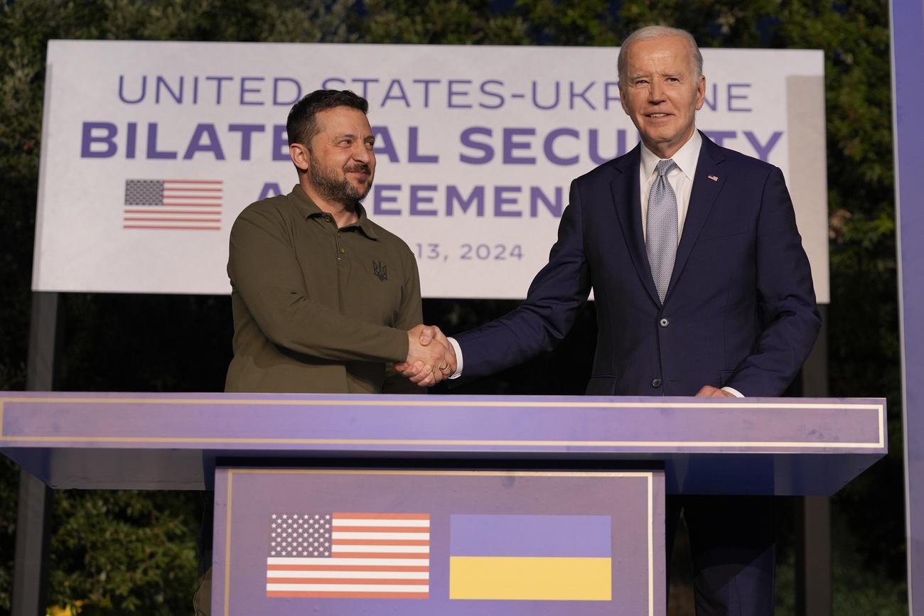 Le président Joe Biden et le président ukrainien Volodymyr Zelenskyy se serrent la main après avoir signé un accord de sécurité bilatéral en marge du G7, le jeudi 13 juin 2024 en Italie. [KEYSTONE - ALEX BRANDON]