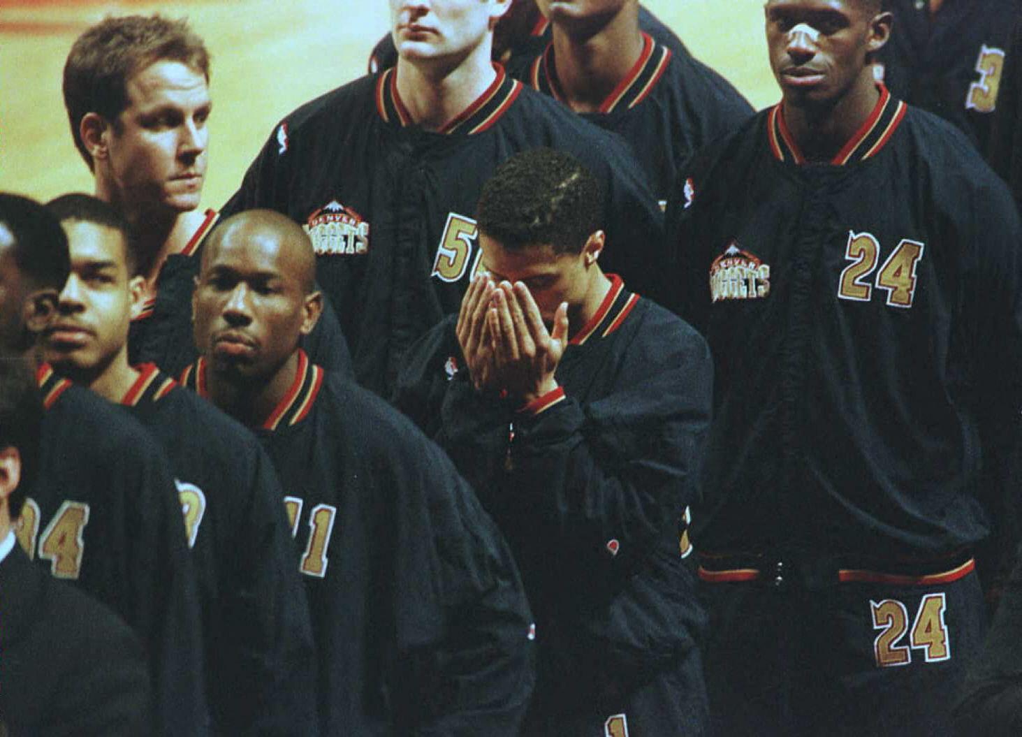Le défenseur des Denver Nuggets Mahmoud Abdul-Rauf (C) incline la tête pour prier, le 15 mars 1996 à Chicago, dans l'Illinois, pendant l'hymne national américain, avant un match contre les Chicago Bulls. Trois jours plus tôt, Abdul-Rauf avait été suspendu pour un match après avoir refusé de se lever pour l'hymne national, le 12 mars 1996. La photo du basketteur en pleine prière est devenu le symbole de son combat contre l'islamophobie aux USA. Il jugeait en outre que le drapeau américain était un « symbole d'oppression », d'où son refus d'entonner l'hymne. [AFP - ERIC CHU]