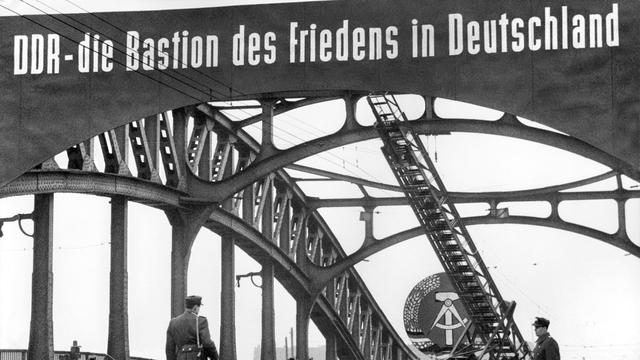 Le 4 décembre 1961, des "policiers du peuple" surveillent le passage de la Bornholmer Strasse sur le pont de la Boesebruecke, entre le secteur français et le secteur soviétique de Berlin. [KEYSTONE - STR]