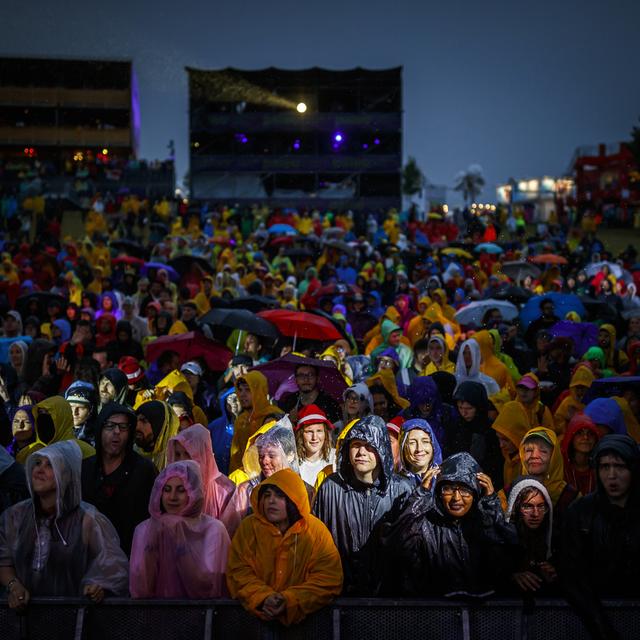 Des festivaliers et festivalières sous la pluie devant la Grande Scène de Paléo en 2018. [Keystone - Valentin Flauraud]