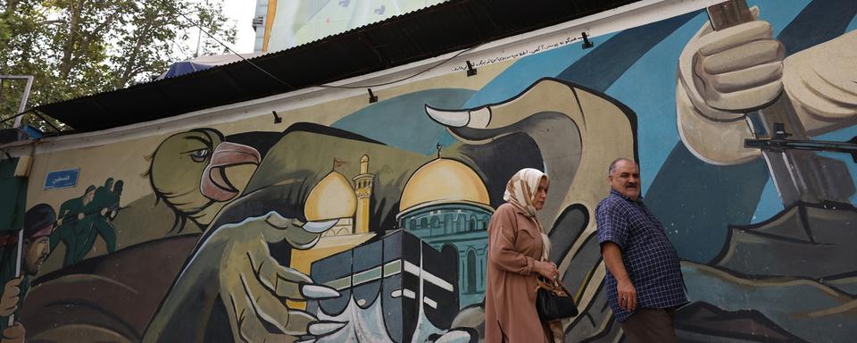 Un couple devant une image murale anti-Israël en Iran. [Keystone/EPA - Abedin Taherkenareh]