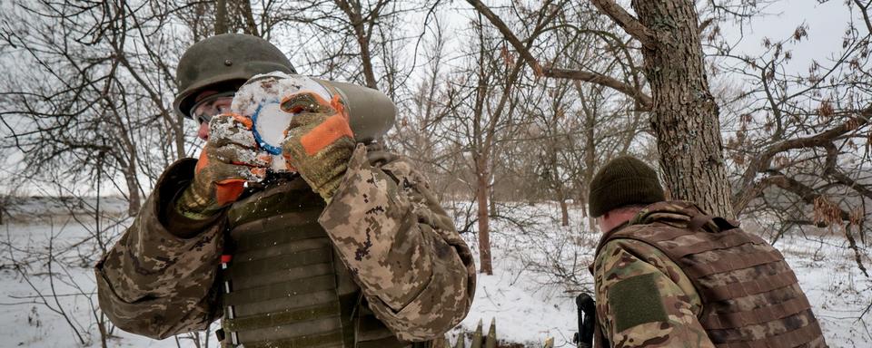 Un militaire ukrainien de la 406e brigade d'artillerie portant le nom du général Oleksii Almazov de Khorunzhoy transporte un obus de 155 mm sur son épaule vers un obusier M777 dans un lieu non divulgué de la région de Zaporizhia, dans le sud-est de l'Ukraine, le 14 janvier 2024, au milieu de l'invasion russe. [KEYSTONE - KATERYNA KLOCHKO]