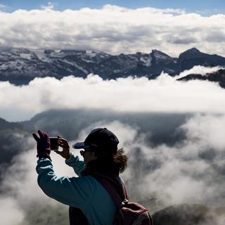 Une touriste prend une photo depuis la montagne du Stanserhorn, en septembre 2018. [KEYSTONE - Jean-Christophe Bott]