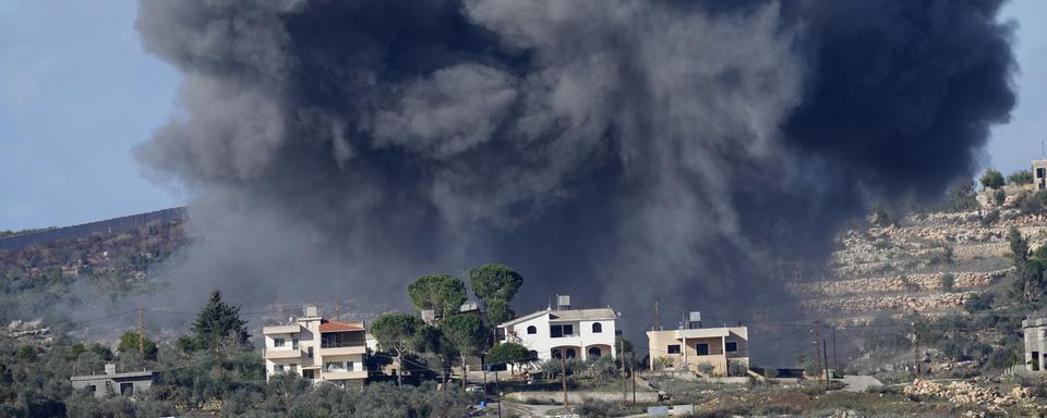 De la fumée noire monte dans le ciel après une frappe israélienne sur le village d'Aita al-Shaab, au Liban. [Keystone - Hussein Malla]