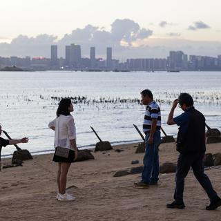 The Xiamen city in China is seen in the background as a people walk next to anti landing spikes installed at the coast of Kinmen County, Taiwan, 03 July 2024. Taiwan has demanded the release of a Taiwanese fishing boat seized by the Chinese coastguard and taken to a port in mainland China on 02 July 2024. The Dajinman 88 was intercepted by two Chinese vessels near the Kinmen archipelago, an area controlled by Taiwan, according to a statement by the Taiwanese coastguard administration. [EPA/Keystone - RITCHIE B. TONGO]