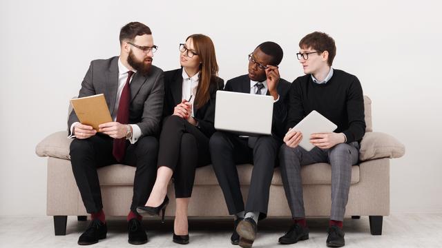 Un groupe de jeunes employés assis sur un canapé. [Depositphotos - Milkos]