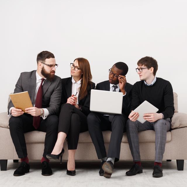 Un groupe de jeunes employés assis sur un canapé. [Depositphotos - Milkos]