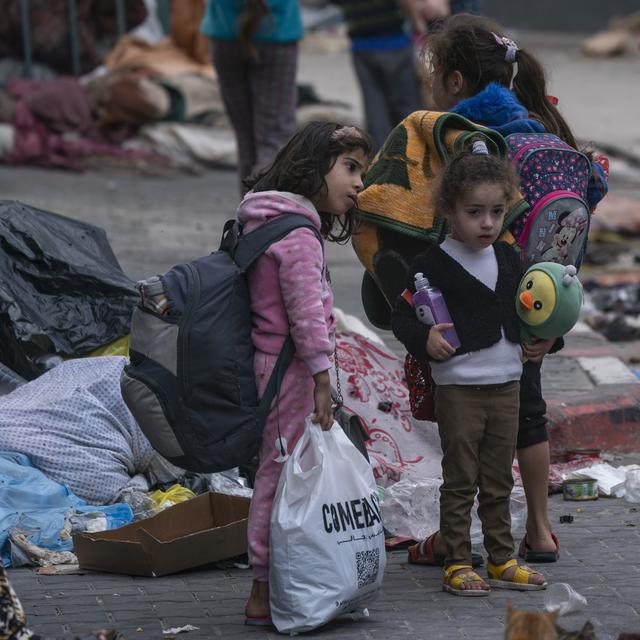 Des enfants palestiniens avec leurs affaires qui attendent avant d'essayer de se réfugier dans un hôpital de Gaza. [Keystone/AP Photo - Victor R. Caivano]