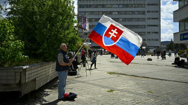 Un homme tient un drapeau de la Slovaquie devant le F. D. Roosevelt University Hospital où est soigné le Premier ministre Robert Fico. [AP Photo/Keystone - Denes Erdos]