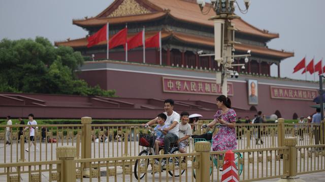 Une famille est photographiée en train de faire du vélo près de la place Tienanmen de Pékin, où le parti communiste chinois tient son troisième plénum, le 15 juillet 2024 (image d'illustration). [keystone - Andres Martinez Casares]