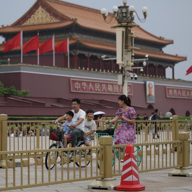 Une famille est photographiée en train de faire du vélo près de la place Tienanmen de Pékin, où le parti communiste chinois tient son troisième plénum, le 15 juillet 2024 (image d'illustration). [keystone - Andres Martinez Casares]