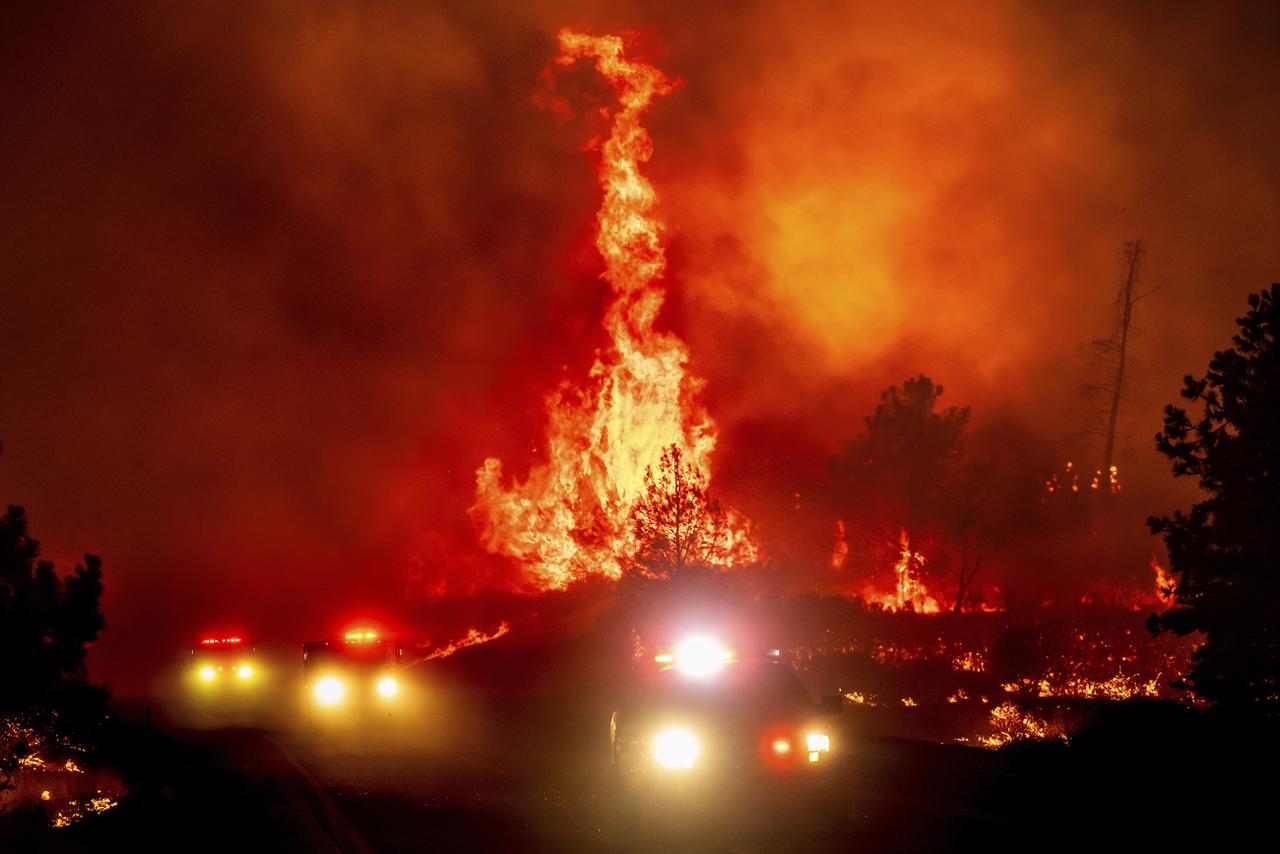 Les flammes s'élèvent au-dessus des véhicules de pompiers alors que le Park Fire saute l'autoroute 36 près de Paynes Creek dans le comté de Tehama, en Californie, le vendredi 26 juillet 2024. [KEYSTONE - NOAH BERGER]