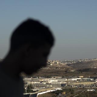 A Palestinian youth stands on a hill overlooking Israel's Ofer Prison, near the West Bank city of Ramallah, Wednesday, July 3, 2024. Released Palestinians have described to The Associated Press worsening abuses in Israeli prisons crammed with thousands detained since the war in Gaza began 10 months ago. [AP Photo/Keystone - Maya Alleruzzo]