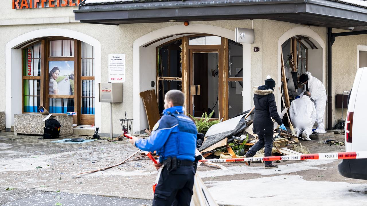 Des membres de la police scientifique de la Gendarmerie vaudoise, inspectent l'explosion du bancomat de la Raiffeisen après un braquage le jeudi 2 février 2023 à Bière. [Keystone - Jean-Christophe Bott]