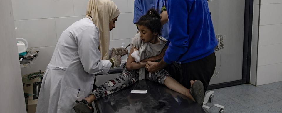 Une petit fille palestinienne est prise en charge dans un hôpital de Rafah. [Keystone - Haitham Imad]