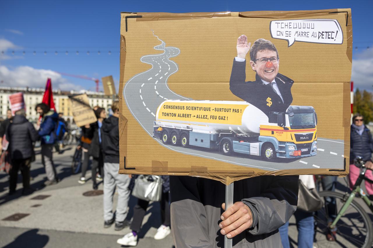 Une personne avec un placard représentant le conseiller fédéral Albert Roesti manifeste contre les projets d'extensions d'autoroutes ce samedi 5 octobre 2024 à Genève. [KEYSTONE - SALVATORE DI NOLFI]