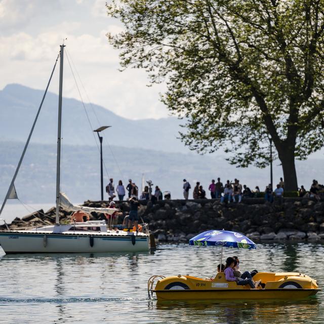 Des personnes profitent du soleil en faisant du pédalo sur le lac Léman. [Keystone - Jean-Christophe Bott]