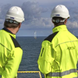 Deux employés belges regardent la construction d'éoliennes off-shore dans la Mer du Nord. [Keystone/Pool Photo via AP - Eric Herchaft]