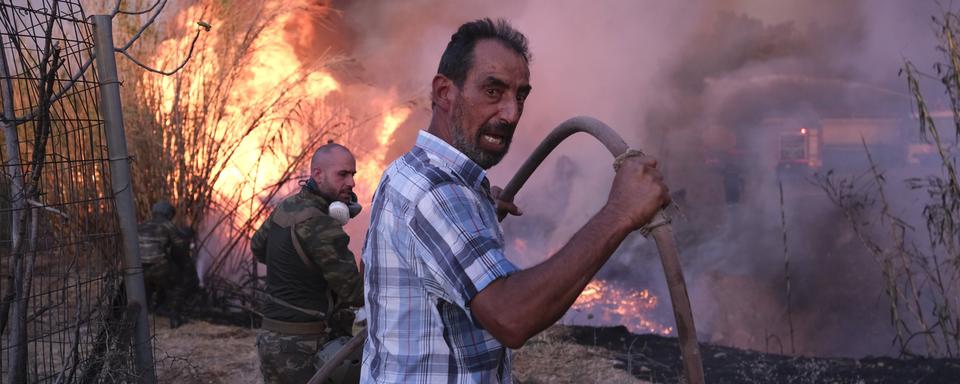 Des volontaires tentent d'éteindre l'incendie dans le nord d'Athènes. [Keystone - Aggelos Barai]