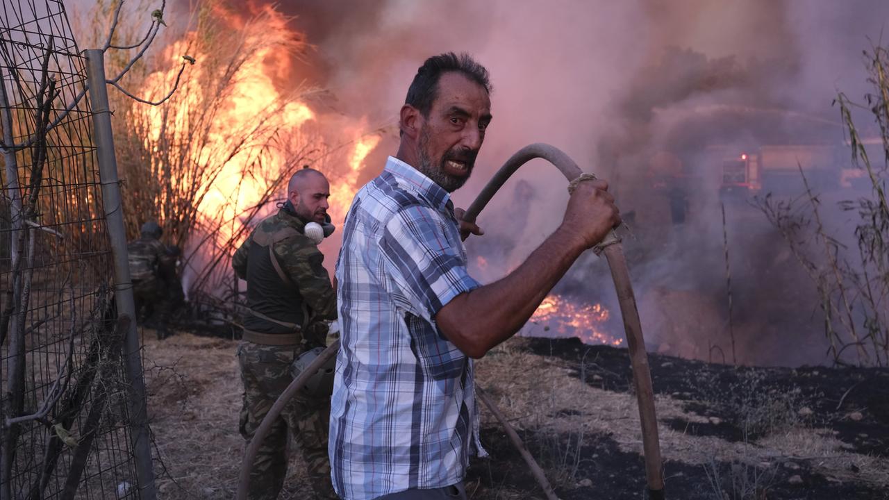 Des volontaires tentent d'éteindre l'incendie dans le nord d'Athènes. [Keystone - Aggelos Barai]