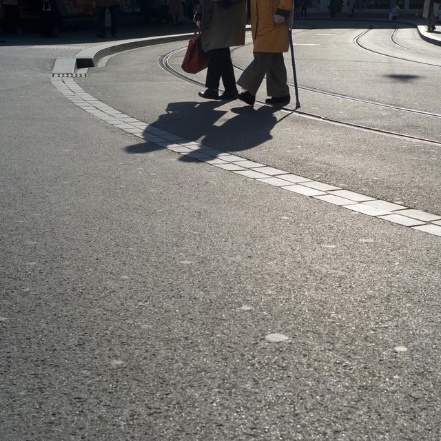 Un couple âgé marchant tranquillement dans une ville. [Keystone - Gaetan Bally]
