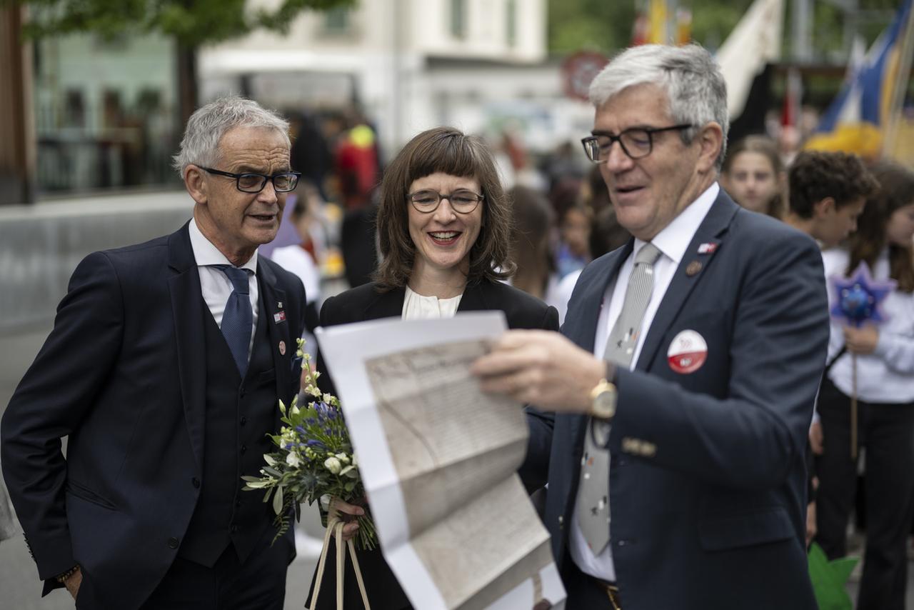 Le président du Parlement Franz Sepp Caluori, la conseillère d'Etat Carmelia Maissen et le président du gouvernement Jon Domenic Parolini étudient une copie de la Lettre fédérale (première constitution du canton), lors de la Journée fédérale, le samedi 1er juin 2024, à Ilanz. [KEYSTONE - GIAN EHRENZELLER]