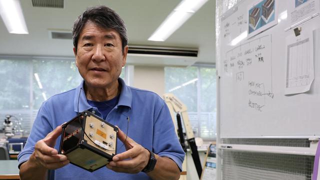 Takao Doi, ancien astronaute japonais et professeur à l'université de Kyoto, tient un modèle technique de LignoSat dans son laboratoire le 25 octobre 2024. [REUTERS - Irene Wang]